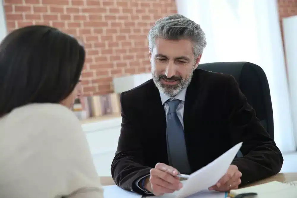 Una persona en una consulta con un abogado, haciendo hincapié en la importancia de una comunicación eficaz con un abogado en los casos de indemnización de los trabajadores.